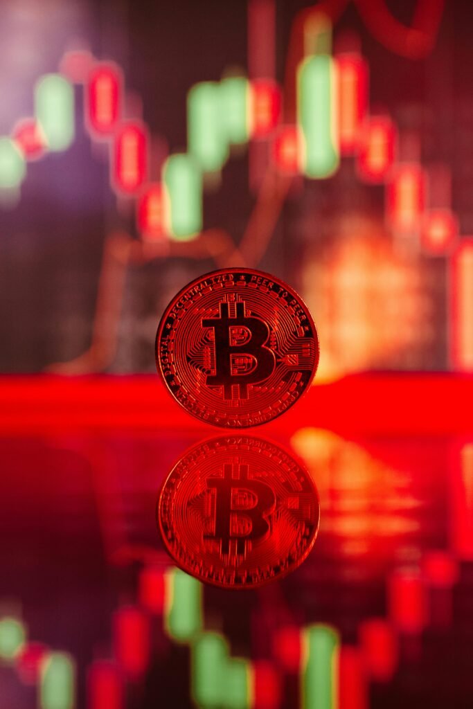 Red Bitcoin coin with reflection against digital trend charts representing cryptocurrency market analysis.