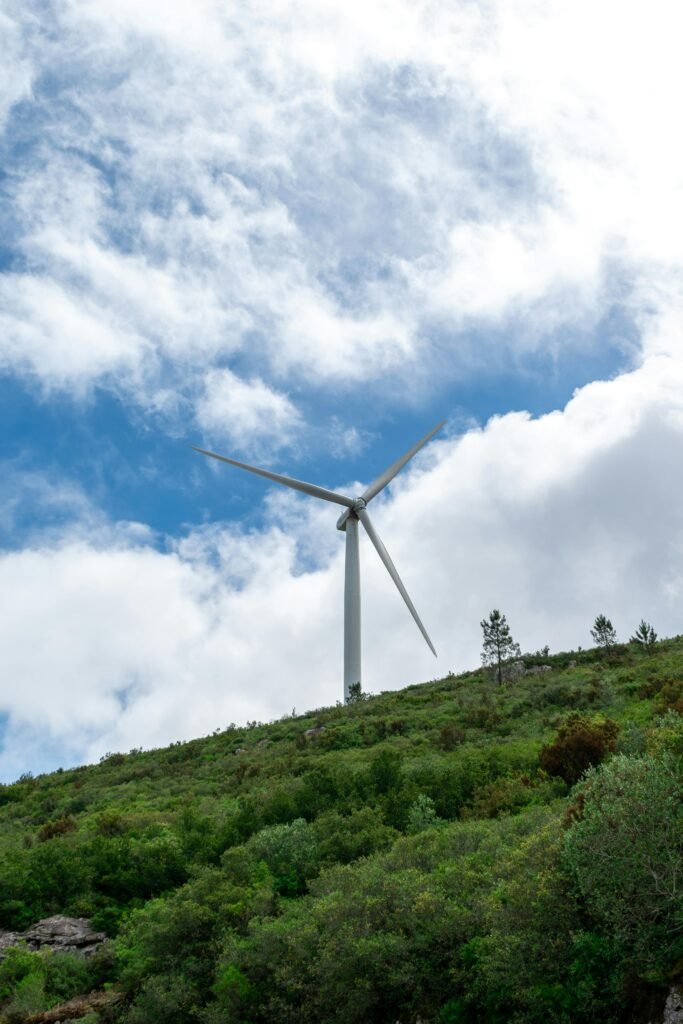 A wind turbine towers over a lush green hillside, highlighting renewable energy in a natural setting.