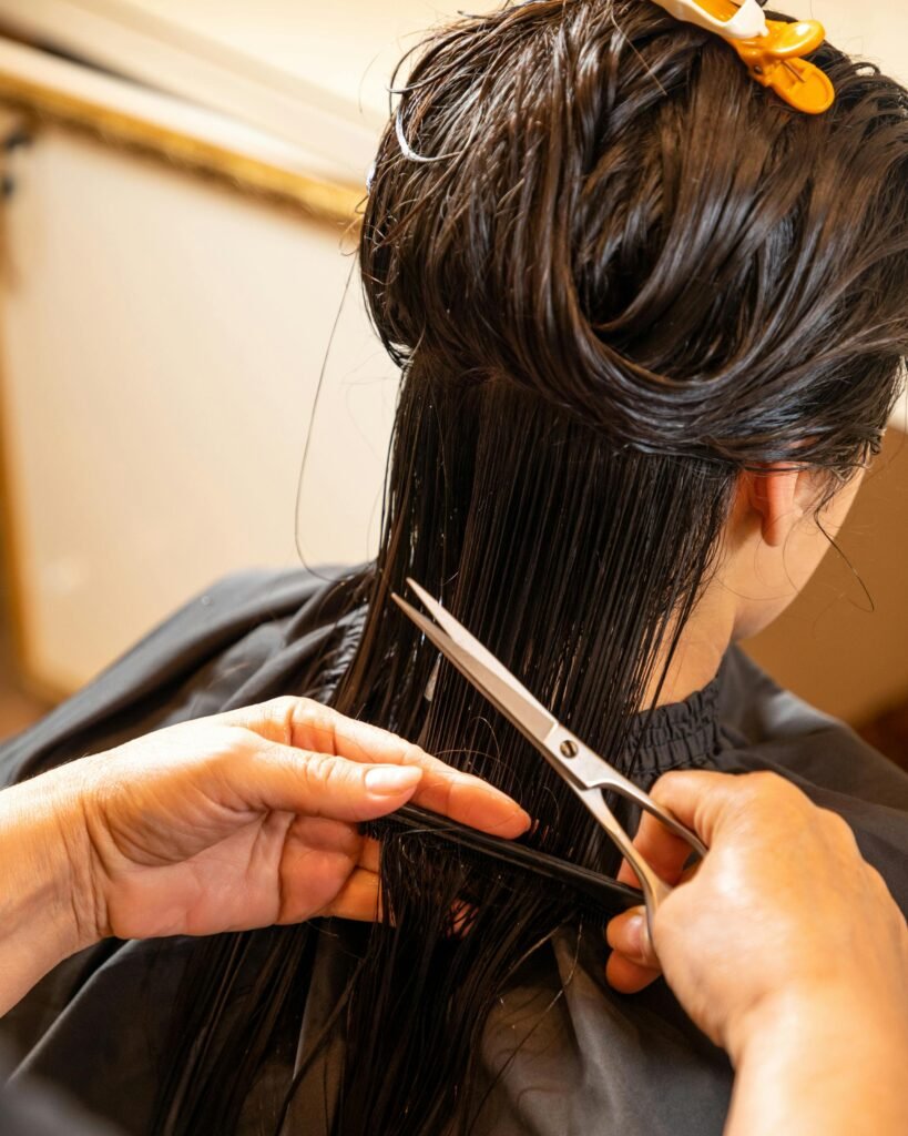 Close-up of a hairstylist giving a woman a haircut with scissors, showcasing professional grooming in a salon.