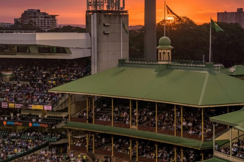 A colorful sunset over a bustling cricket stadium, capturing the lively atmosphere of the event.