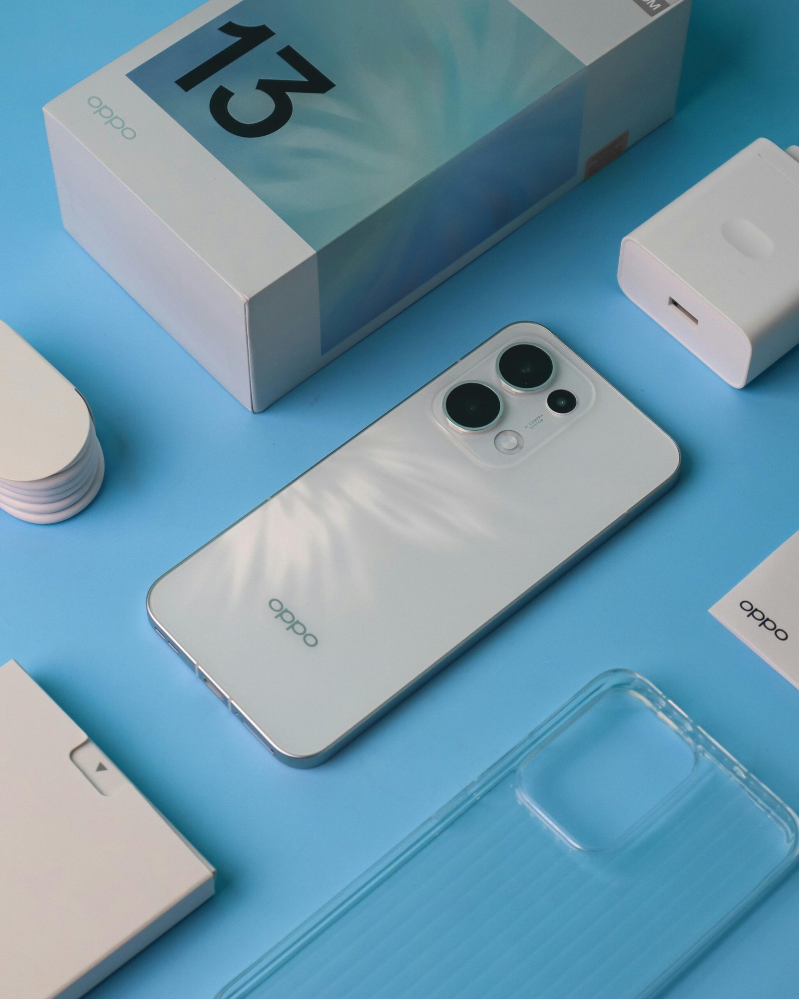 Flat lay of a new smartphone with accessories on a blue background.